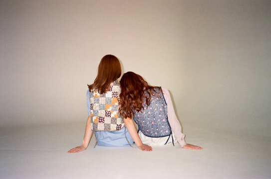 Unrecognizable girls sitting on cyc wall floor 