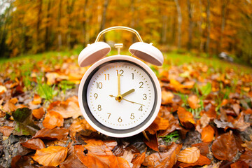 Alarm clock with autumn foliage, end of daylight saving time in fall, winter time changeover