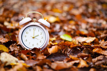 Alarm clock with autumn foliage, end of daylight saving time in fall, winter time changeover