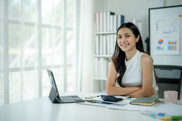 A woman is sitting at a desk with a laptop and a calculator