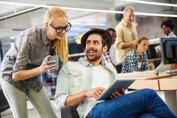 Young professionals collaborating with digital tablet in busy office