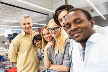 Diverse group of coworkers smiling together for selfie in a modern office setting