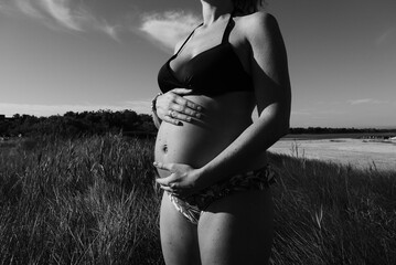 A faceless pregnant woman in summer on a beach