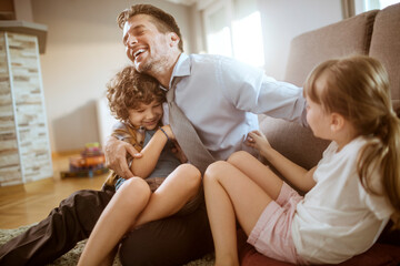 Happy father playing with son and daughter at home