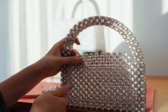 Young girl crafts bead handbag. Artisan handicraft and Hobby