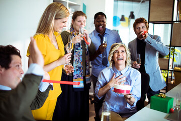 Office birthday celebration with colleagues enjoying drinks and cake