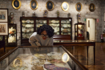 Woman visitor in the historical museum looking at art object.