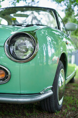 A green vintage car is parked in the shade of the trees. Oldtimer car. Classic vehicle.	
