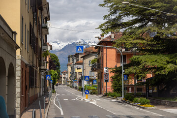 a view of the main street in bellano Italy with snow capped mountains in the background