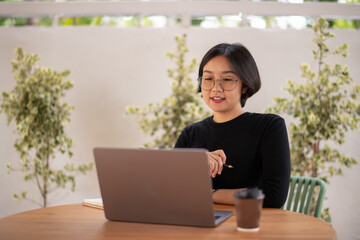 A woman is sitting at a table with a laptop in front of her