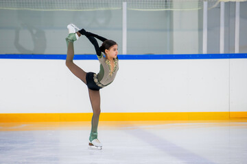 A young girl is skating on ice with a smile on her face. She is wearing a black outfit and is wearing gloves