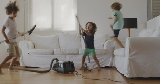 Three kids are joyfully cleaning a living room with a vacuum, appearing to dance and enjoy their housework.