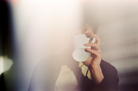 Anonymous person drinking from a white mug cup morning coffee 