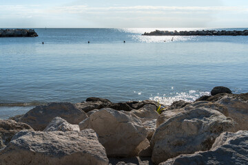 Tranquil seascape with foreground boulders, serene water, clear skies – perfect for calm-themed visuals