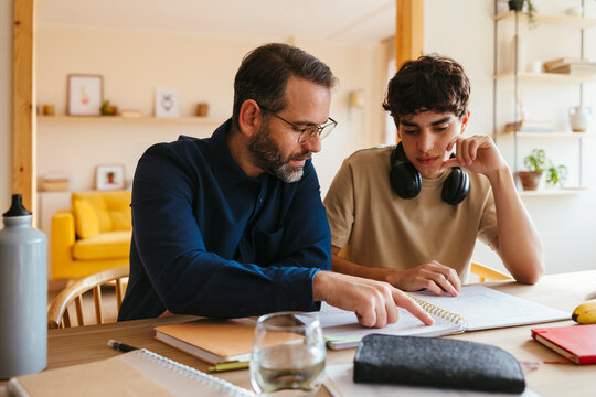 Father and son doing homework at home - Powered by Adobe