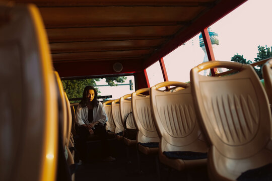 a young girl sitting alone in the back row of seats on a bus.