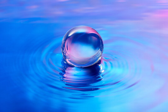 Crystal ball leaving waves in water surface with iridescent gradient