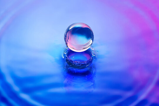 Crystal ball making splashes on water with blue and pink color