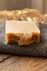 A piece of natural household soap and towel on wooden background. Soft focus