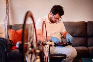 A mechanic wearing blue gloves organizing tools in a workshop, with a bicycle wheel in the...