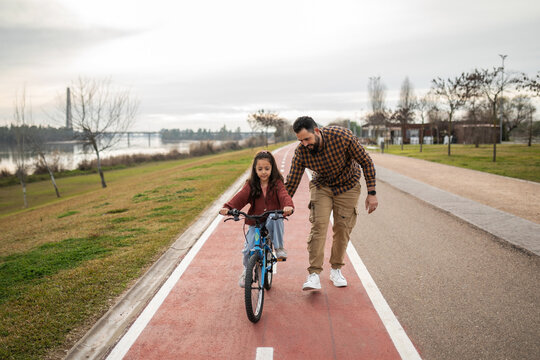 father teaching his daughter to ride a bicycle
