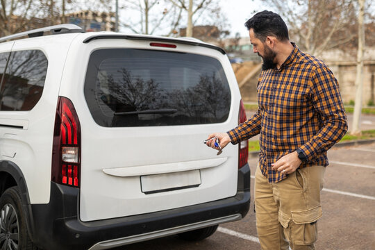 bearded young man locking his car in a city parking lot