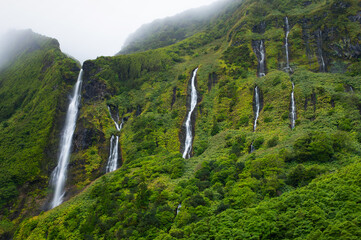 Cascata da Ribeira do Ferreiro, Flores Island, Azores, Portugal. Long exposure waterfalls. Waterfall with  tropical green vegetation and forests. Travel destination. Hiking on Azores Islands.