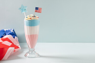 American layered milkshake, ice cream or sweet dessert in red, white and blue colors on blue...