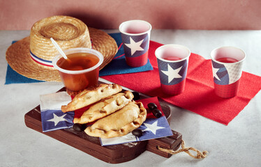 empanadas de pino y mote con huesillos junto a vasos con bandera de Chile, celebración fiestas...