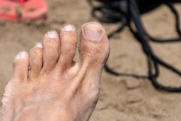 Selective focus on an adult male foot in the sand on the beach.