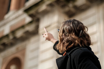 Unrecognizable tourist woman pointing at an historical building.
