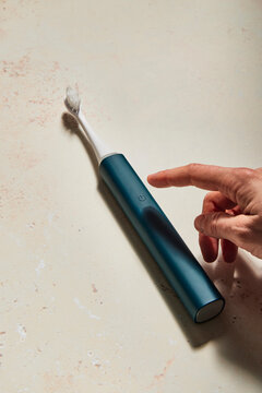 Hand turning on blue electric toothbrush