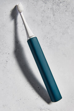 Blue electric toothbrush leaning on the wall 