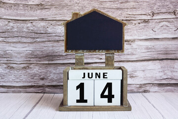 Chalkboard with June 14 date on white cube block on wooden table.