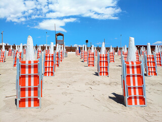 Closed deckchairs and umbrellas on a beach, a symbolic image of the preparations for the summer...