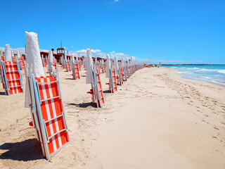 Closed deckchairs and umbrellas on a beach, a symbolic image of the preparations for the summer...