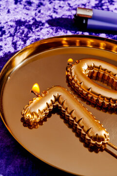 lit candles forming the number 70 on a golden metal tray
