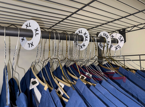 Size Uniforms on Coat Hangers in closet rack 
