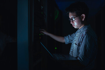 Computer engineer is setting up network in server room,Systems Maintenance Technician,Male engineer working in server room at modern data center