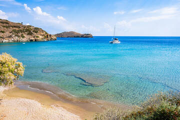 Secluded sandy beach and catamaran boat in sea bay near Chrysopigi monastery, Sifnos island, Greece
