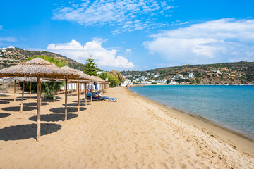 Sun loungers and umbrellas in Platis Gialos village on sandy beach with sea view, Sifnos island,...