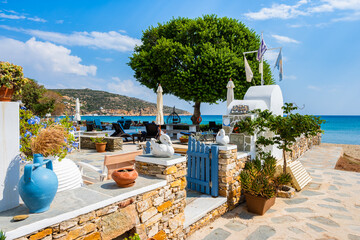 Beautiful architecture of Platis Gialos village with colorful flowers in pots near beach, Sifnos...