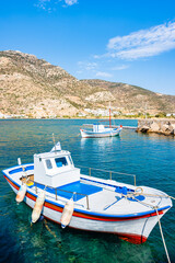 Traditional colorful Greek fishing boats anchoring in Kamares bay port and mountains in background,...