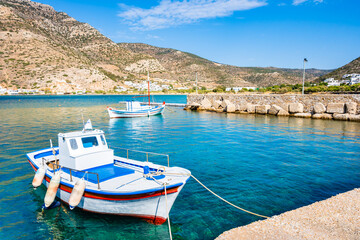 Traditional colorful Greek fishing boats anchoring in Kamares bay port and mountains in background,...