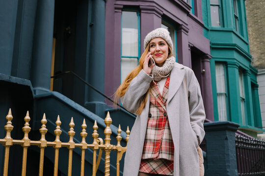 A woman in a red plaid suit walks during a phone call