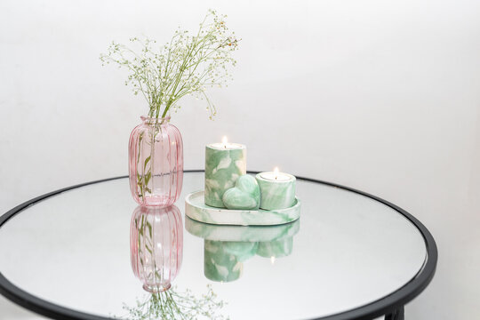 Modern Pink Vase and Green Marbled Candles on Reflective Surface.
