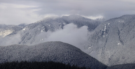 Panorama of snow-covered mountains in a cloudy day