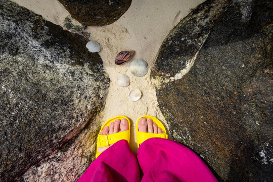 Female feet in yellow sleepers on the beach
