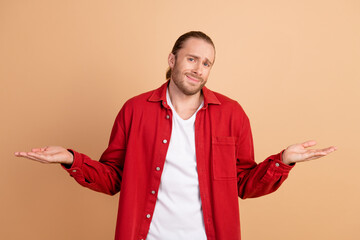 Photo of nice young man shrug shoulders wear red shirt isolated on beige color background