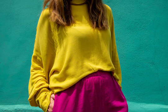 Anonymous female in front of a turquoise wall in colorful clothes